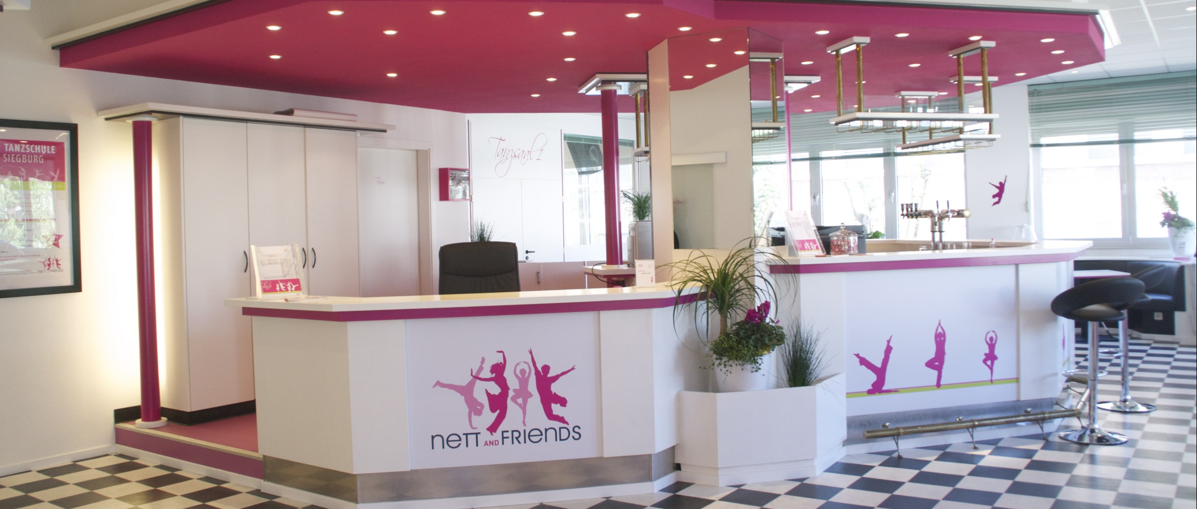 Großes Foyer mit pinker Theke und Cafébereich – einladend und freundlich gestaltet.