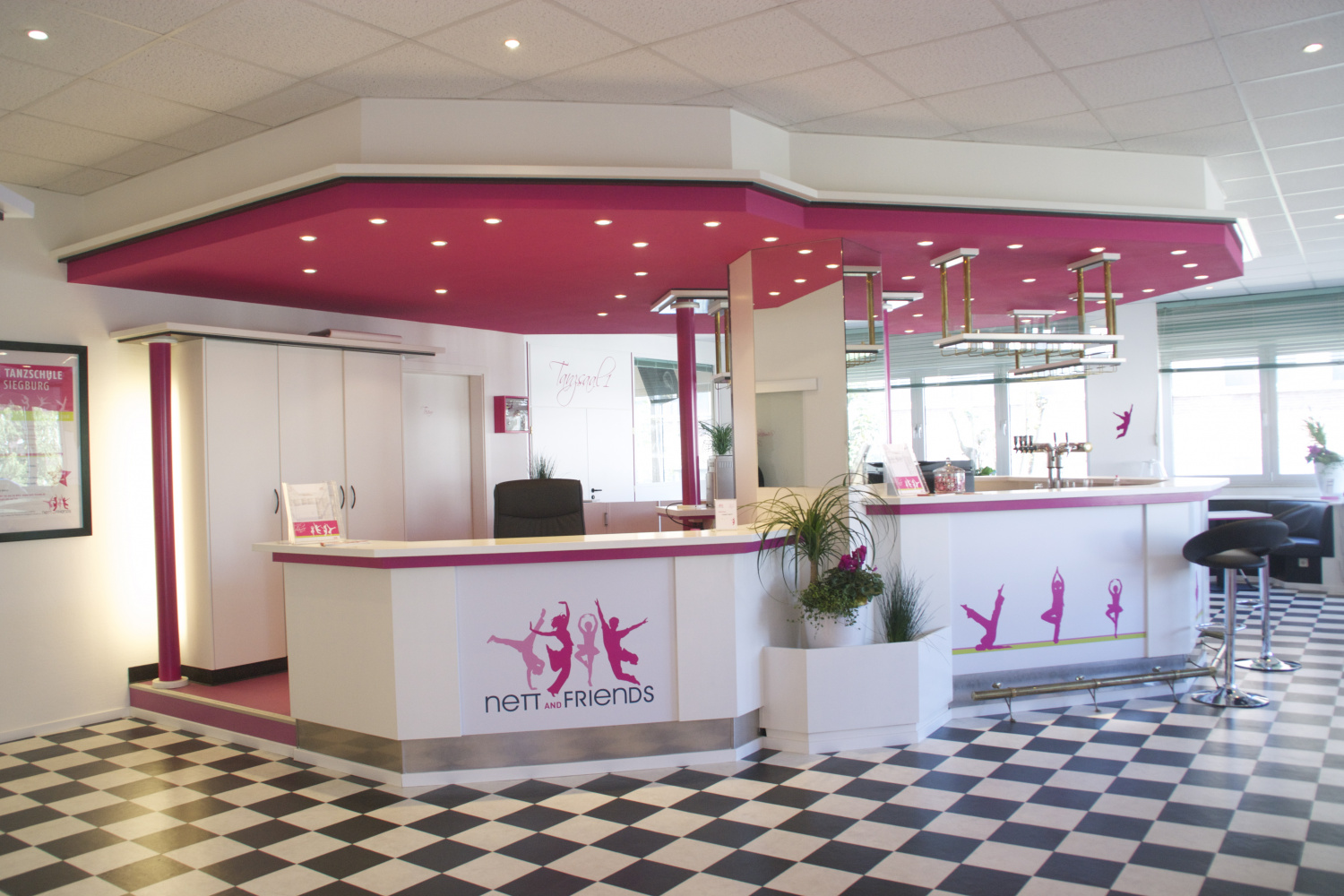 Großes Foyer mit pinker Theke und Cafébereich – einladend und freundlich gestaltet.