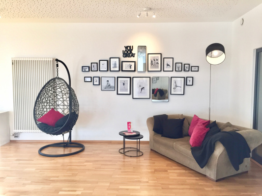 Gemütliches Sofa im Tanzsaal mit kunstvollen Bilderrahmen im Hintergrund – modernes, kreatives Studioambiente.