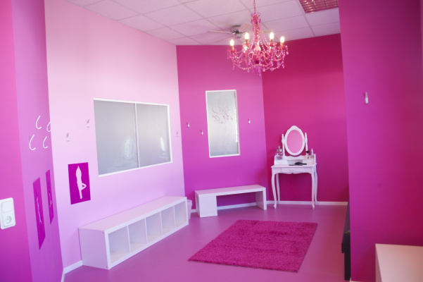 Knall-pinke Damenumkleide mit pinkem Kronleuchter und stilvoller Wandgestaltung.